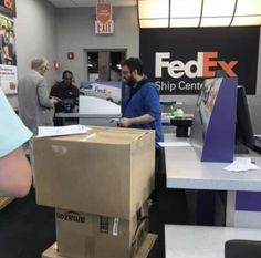 some people are standing around with boxes on the table and one person is holding a computer