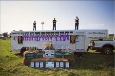 three men standing on the roof of a white trailer with purple ribbons hanging from it