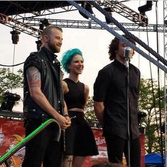 two men and a woman on stage with microphones