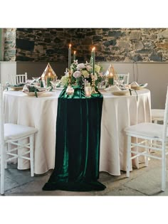 the table is set with white and green linens, candles, and flowers on it