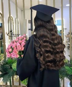 a woman with long hair wearing a graduation cap and gown