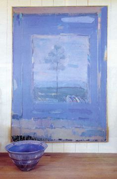 a blue bowl sitting on top of a wooden table in front of a large painting