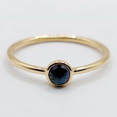 a gold ring with a blue stone in the center and a thin band around it