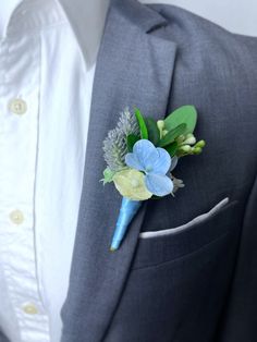 a boutonniere with blue flowers and greenery on the lapel of a man's suit