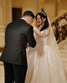 a bride and groom standing in front of the stairs at their wedding ceremony, looking at each other