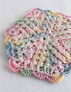 a crocheted dishcloth is shown on a white surface with blue, pink, and green colors