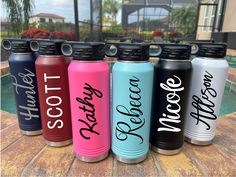 six personalized stainless steel water bottles sitting on a brick patio next to a swimming pool