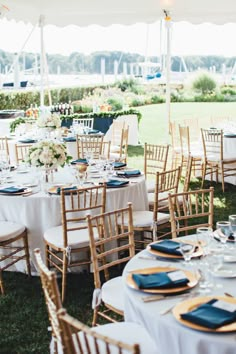 an outdoor wedding reception setup with blue and gold place settings