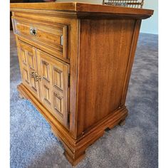 an old wooden cabinet with two doors and drawers on the bottom, sitting on carpeted floor