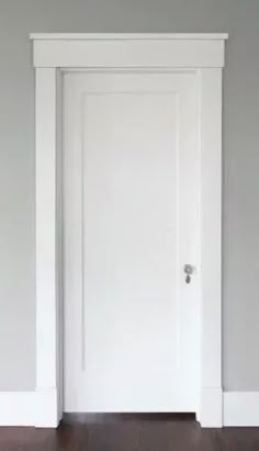 an empty room with a white door and hard wood floor