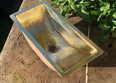 a square glass sink sitting on top of a brick wall next to a planter