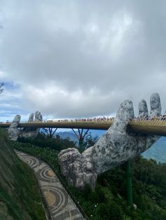 people are standing on the top of a bridge with their hands in the air above them