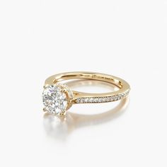 a yellow gold engagement ring with an oval cut diamond in the center and pave set shoulders