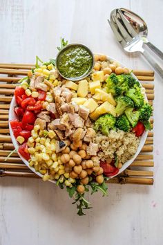 a bowl filled with different types of food on top of bamboo sticks next to a fork and spoon