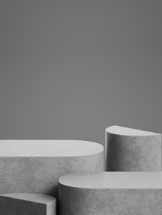 two concrete benches sitting next to each other in front of a gray wall and floor