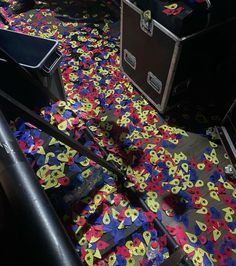 the floor is covered with colorful confetti and black cases in an office building