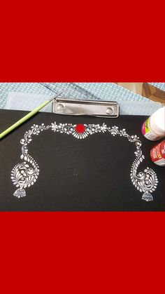 a black cutting board with white designs on it next to paintbrushes and a pair of scissors