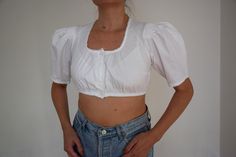 Vintage cropped dirndl blouse with short puffy sleeves, size 36 EU / 6 US Women's white cropped top with a buttoned front  and elastic hem under the bust.  The blouse has beautiful pin tuck handwork on the shoulders which give it more volume. The hems of the neckline and sleeves are decorated with delicate lace. Made from high quality thick fabric Material - 100% cotton Size - 36 DE which corresponds to 6 US, Shown on size 38 EU, cup size A  Approximate Measurements (taken when top is lying flat White Dirndl, Blouse Crop Top, Blouse Crop, Dirndl Blouse, Cropped Tops, Cropped Tube Top, Puffy Sleeves, Boho Festival, Peasant Blouse