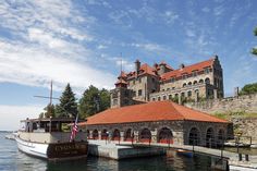 a boat that is sitting in the water next to a large building with a red roof