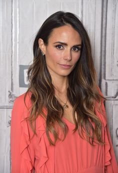 a woman in an orange dress poses for a photo on the set of her show