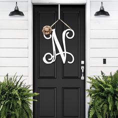 a black front door with a white monogrammed number on it and some plants