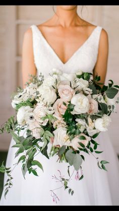 a bride holding a bouquet of white and pink flowers