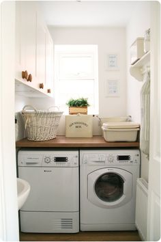 a washer and dryer in a small room with wooden counter tops on the side