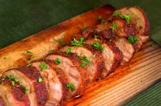 some meat is laying on a wooden board with parsley sprinkled around it