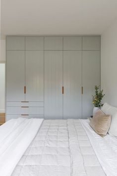 a white bed sitting in a bedroom next to wooden cabinets