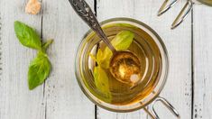 an overhead view of a cup of tea with leaves and spoons on the side