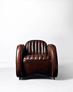 a brown leather chair sitting on top of a white floor