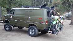 an army green van with bicycles strapped to the back