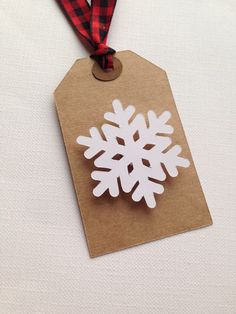 a paper snowflake ornament hanging from a brown tag on a white background