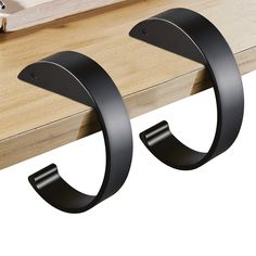 two black metal hooks on a wooden shelf