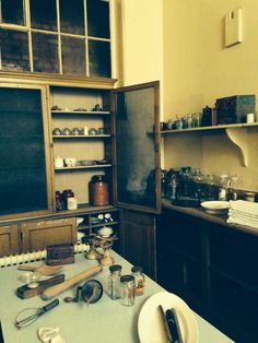 an old fashioned kitchen with many items on the counter and shelves in front of it