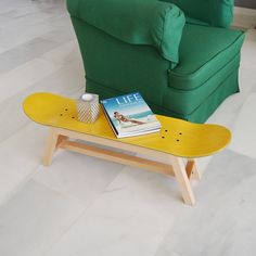 a yellow skateboard sitting on top of a wooden table next to a green couch