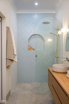 a walk in shower sitting next to a sink and a wooden counter top under a mirror