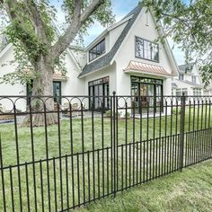 a large white house with a black fence in front of it and a big tree