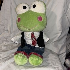 a stuffed frog wearing a suit and tie sitting on a white chair with a red checkered tie