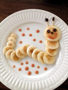 a white plate topped with pancakes and a caterpillar made out of banana slices