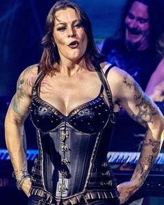 a woman wearing a corset and holding her hands on her hips while standing in front of a keyboard