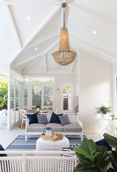 a living room filled with furniture and a chandelier hanging over the top of it