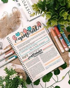 an open planner sitting on top of a table next to some flowers and other items