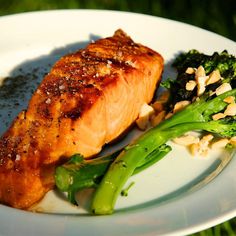 a white plate topped with salmon and broccoli