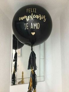 a black balloon with writing on it hanging from the ceiling in front of a mirror that says, feliz cumpleanos te amo