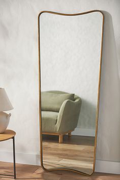 a large mirror sitting on top of a wooden floor next to a table and chair