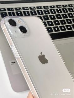 an iphone case sitting on top of a laptop computer next to a hand holding it