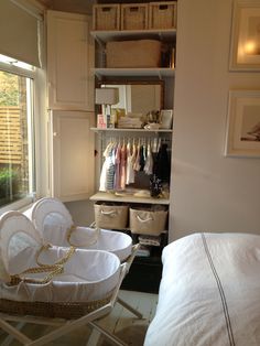 a closet with clothes and baskets in it next to a bed, dresser and window