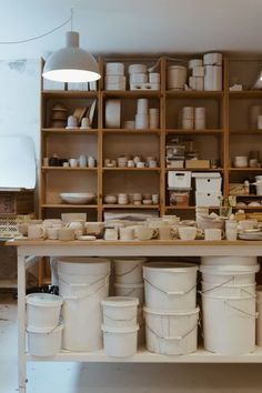 many white buckets are stacked on a shelf