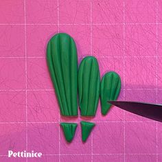 a pair of scissors cutting green plastic cactus shapes on a pink background with the words pottince written below it